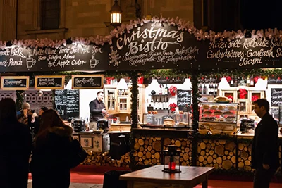 Christmas Bistro written in white on the facade of a festively decorated food booth at night