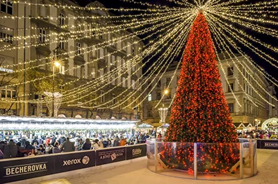 An artificial Christmas tree decorated in all red standing in the middle of the ice rink on Szt. István Square
