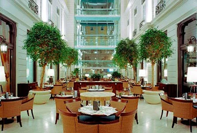 tables and chairs, green plants in the light atrium of Corinthia