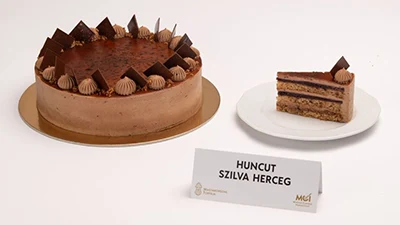 The whole plum/chocolate mousse cake and a slice from it placed on a round white plate