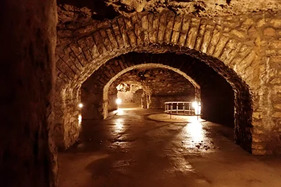 a tunnel with a series of vaults illuminated with spot lamps in the Labyrinth of Buda castle