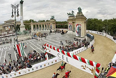 a sand covered course with horse racers racing on it at Heroes' Sqr's monuments 