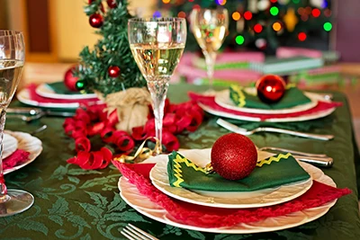 festive Christmas table setting in red and dark green, with 2 glasses of champagne