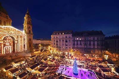 birds'eye view of the Christmas fair in front of St. Stephen Basilica at night, the ice rink and the Christmas Tree in the middle of it illuminated in blueish pink
