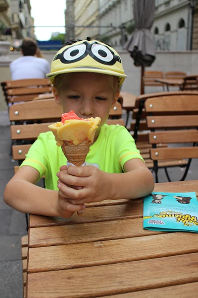 our 6 years old boy holding the rose-shaped ice cream in cone in his hands, he is wearing a yellow Minion's baseball cap