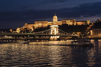 view of the illuminated Royal Palace in Buda and the Chain Bridge at night
