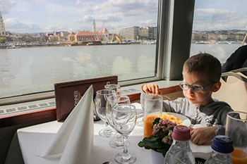 A blonde 6-yr old son eating lunch on the cruise on budapest cruise with lunch