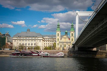 View of the Pest end of the white Elizabeth bridge and the green twin towers of the Inner City Parish Church on a slightly cloudy afternoon on budapest cruise with lunch