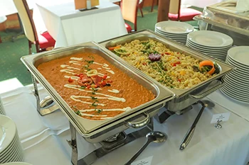 chicken paprikash and dumplings in  square shape stainless steel containers placed on a buffet table covered with white table cloth