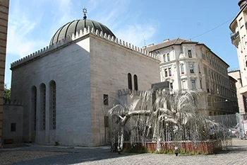 The domed, grey building of the Heroes' Temple with the silver Tree of Life memorial sculpture in front of it.