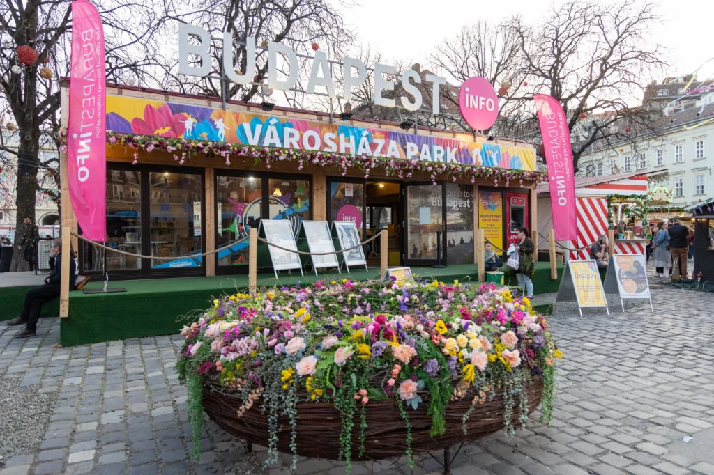 The information office at the Spring and Easter Fair at Városháza Park. A large, colorful flower wreath in front of the building.