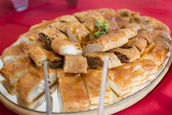 strudel slices with various filling: apple, cottage cheese, ground poppy seed on a tray placed on table with red table cloth