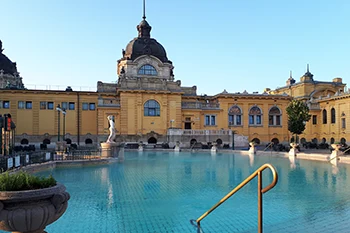 photo showing the large outdoor pool and the yellow facade of the Séchenyi bath