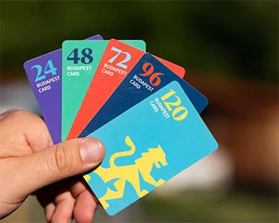 A hand holding the 5 Budapest cards of various durations (each duration has a unique colour) on Why visit budapest