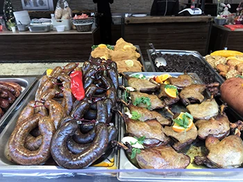 black pudding, roast sausage, and duck placed on stainless steel trays at the Spring and Easter Fair in Budapest, Vörösmarty Square