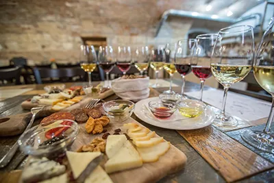 several glasses of red and white wine and cheese and salami platter on a rustic wooden table
