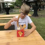 our 10-year old son eating churros sitting at a table at the wine fest