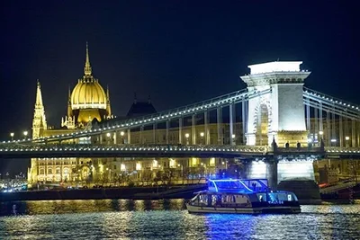 Silver Line cruise boat illuinated at night as it glides on the Danube under the Chain Bridge