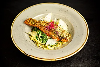 roasted salmon fillet with herb crust on a bed of spinach and tagliatelle