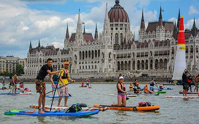 people stand-up paddling on the Danube with the Parliament building in the background