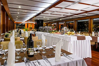the buffet style dinner on a white table clothed table, tables elegantly set for dinner by the panorama windows of the Count Szechenyi Cruise Ship