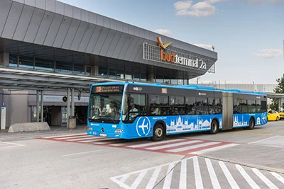 the blue 100E Airport Express shuttle bus in front of Budapest Airport terminal 2A