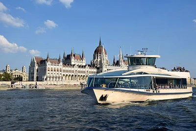 a sightseeing boat sailing on the Danube in front of the Parliament building at daytime