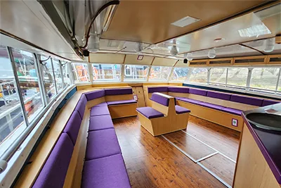 Interior of the catamaran cruise boat: purple upholstered wood sofa and seat bench