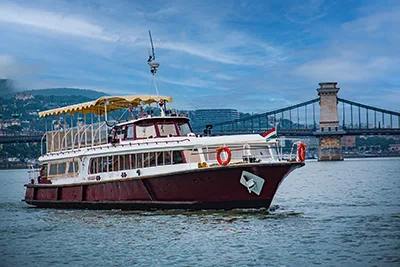 a small catamaran cruise ship on the Danube near the Chain bridge in Budapest during the day