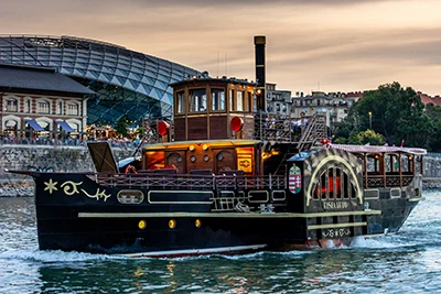 the black, vintage steam boat, Kisfaludy cruising on the Danube near the Whale building.
