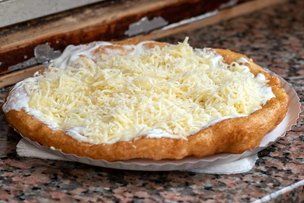 Langos - a round deep-fried pastry with sour cream and grated cheese topping