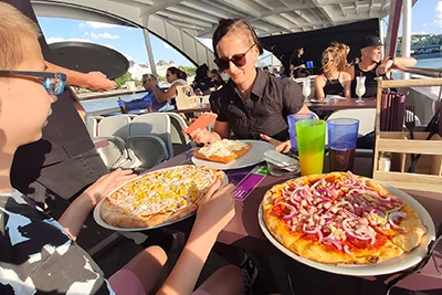 our son eating his bacon and corn pizza, me having lángos with sour cream and cheese on the top deck of the cruise boat