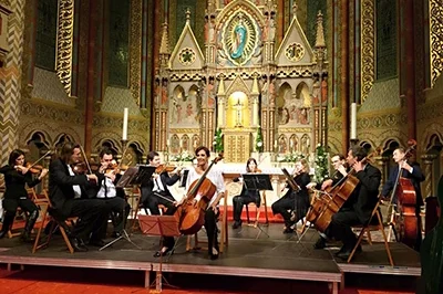 An orchestra playing in front of the ornate main alatra of Mathhias Church