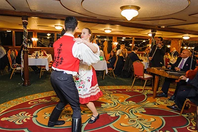 folk dancers - a man & woman - dressed in traditional costume performing onboard a cruise ship