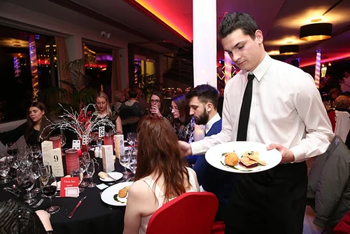 a waiter serving dinner at a table on a NYE cruise party in Budapest