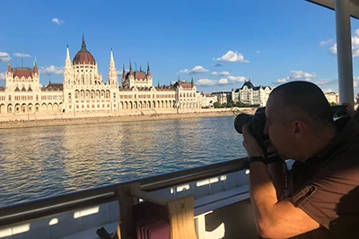 my husband shooting photos of the Parliament from a terrace of a sightseing boat on the Danube on a sunny summer afternoon