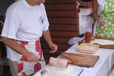 a man in white t-shirt and apron coating the pastry in sugar