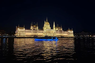 a cruise ship sailing past the Parliament at night