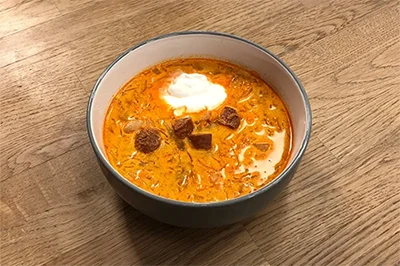 cabbage soup with sour cream and sausage slices in a a bowl