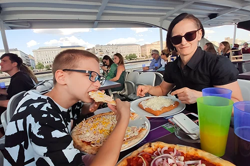 Our son eating corn and ham pizza and me eating lángos on the boat's deck
