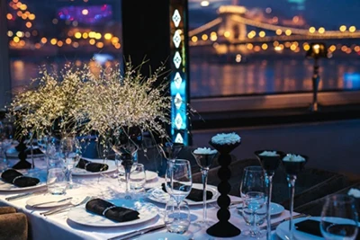 dinner tables festively set onboard a boat prepared for a budapest new year's eve party