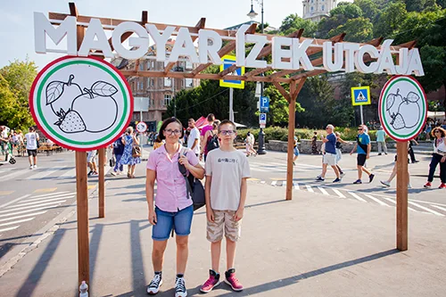 me and my son at the wooden gate entrance to the Street of Hungarian Flavours festival
