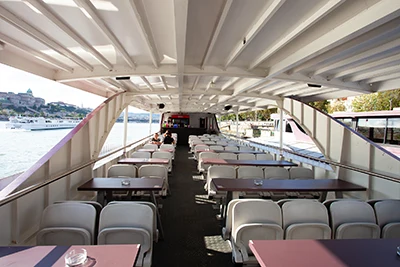 Rows of seats - whiet plastic chairs and purple tables - on the partially open upper deck of the Wiking sightseeing boat