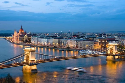 birds' eye view of the Chain Bridge and the Danube at dusk, a cruise ship is gliding under the bridge