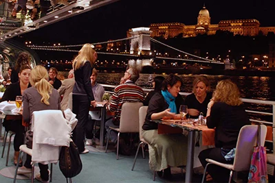 diners sitting around tables on a boat excursion at night in Budapest