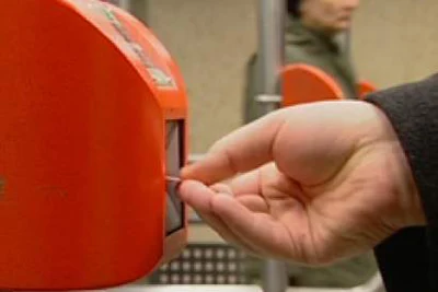 photo showing a hand inserting a metro ticket in the orange-coloured validating machine