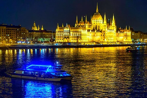 a cruise boat illuminate din blue LED light sailing on the Danube near the Parliament
