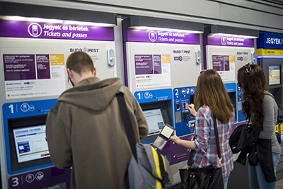 three young people buying tickets from a ticket vending machine