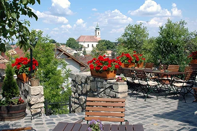 a wine estate in Etyek village with potted red geraniums at ist entrance, a church can be seen in the distance