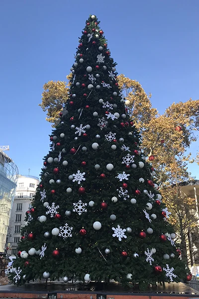 a tall Christmas tree with red and wgite ornaments standing in Vörösmarty Square